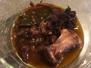 Authentic Jamaican Oxtail Stew with Black Beans and bay leaf in clear glass bowl. The meat is falling off the bone; for Single Ingredient Groceries.