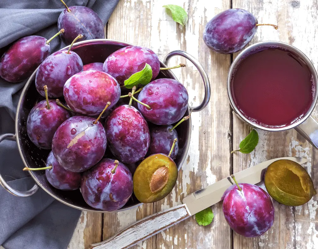 bowl of plums displayed on a wood background