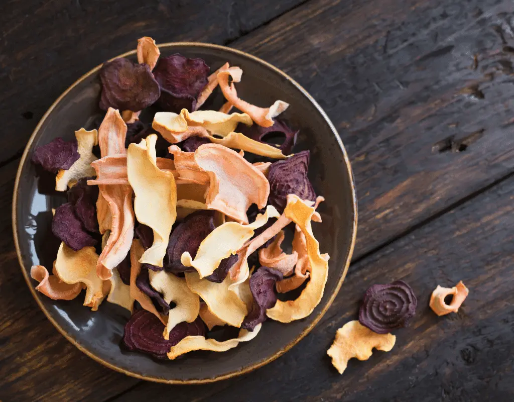 dehydrated veggie chips in a bowl on a dark wooden background