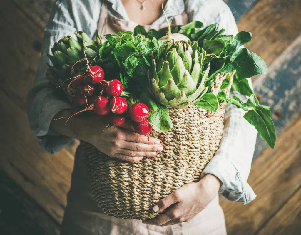 garden vegetables in a wicker basket held by a woman