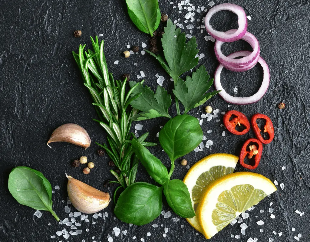 Rosemary, salt, lemon, onion rings, basil and parsley displayed on slate