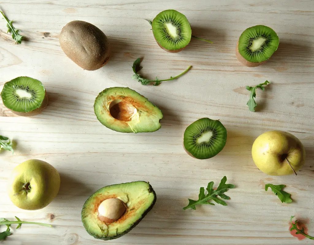 halved avocados and kiwi on a wooden background