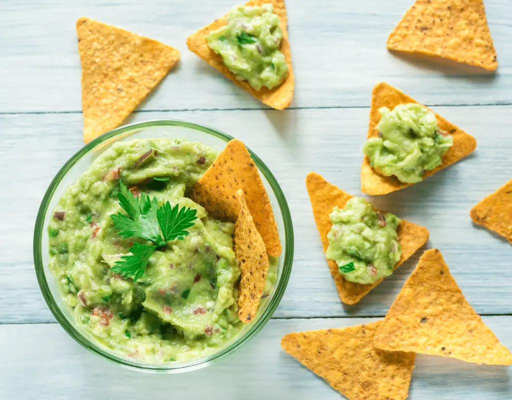 guacamole in a bowl with torilla chips on a blue background for avocado allergy