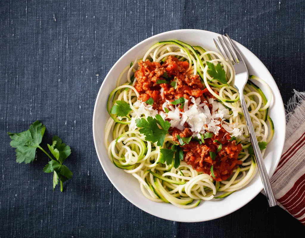 zoodles with a tomato sauce on a white plate