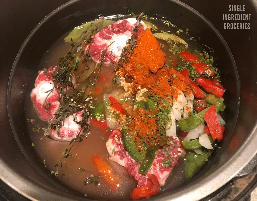 frozen vegetables, herbs, and oxtails in a pot