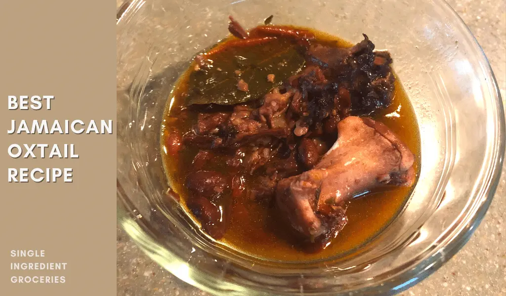 Photo of Jamaican oxtail with meat falling off the bone along side black beans and a bay leaf; Text is: Best Jamaican Oxtail Recipe. 