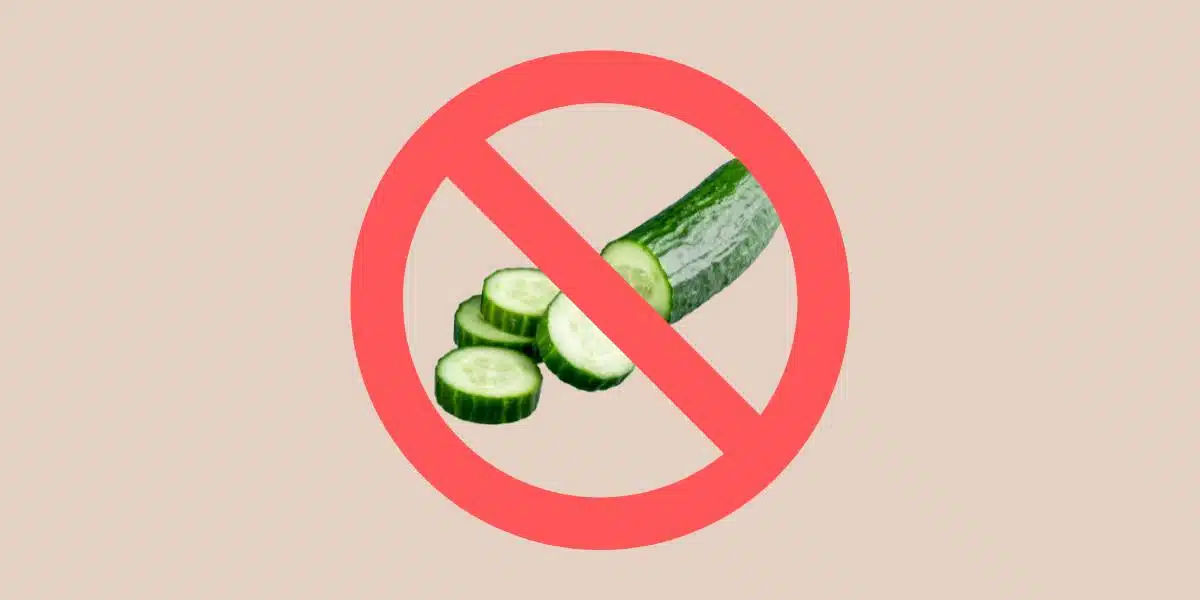 Green cucumber partially sliced on tan background with red no / prohibition sign over it for blog post about cucumber allergy for Single Ingredient Groceries.